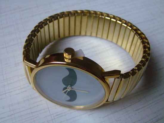 Auksinės spalvos laikrodis su ūsais